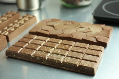 Photo of Different tasty Dubai chocolate bars with pistachios and knafeh on grey table, closeup