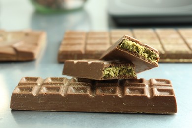 Photo of Tasty Dubai chocolate with pistachios and knafeh on grey table, closeup