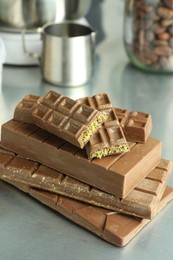 Photo of Stack of tasty Dubai chocolate bars with pistachios and knafeh on grey table