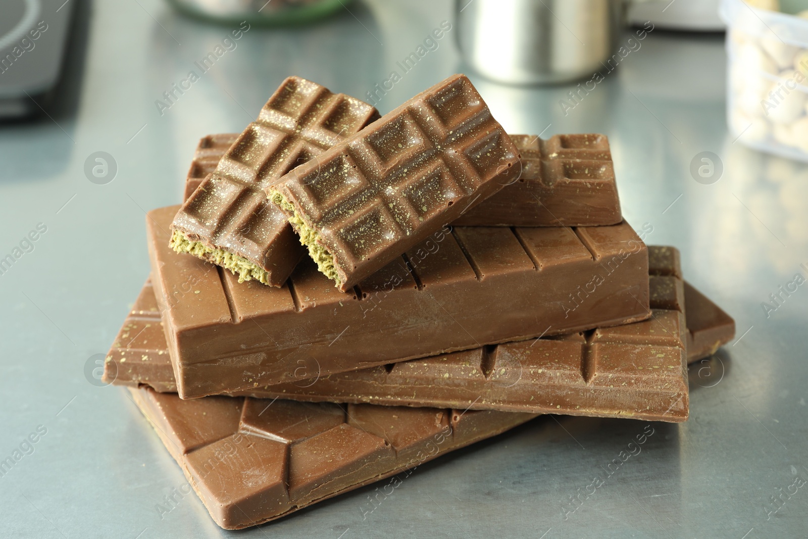 Photo of Stack of tasty Dubai chocolate bars with pistachios and knafeh on grey table, closeup