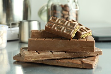 Photo of Stack of tasty Dubai chocolate bars with pistachios and knafeh on grey table, closeup