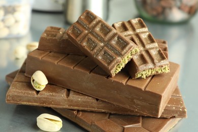 Photo of Stack of tasty Dubai chocolate bars with pistachios and knafeh on grey table, closeup