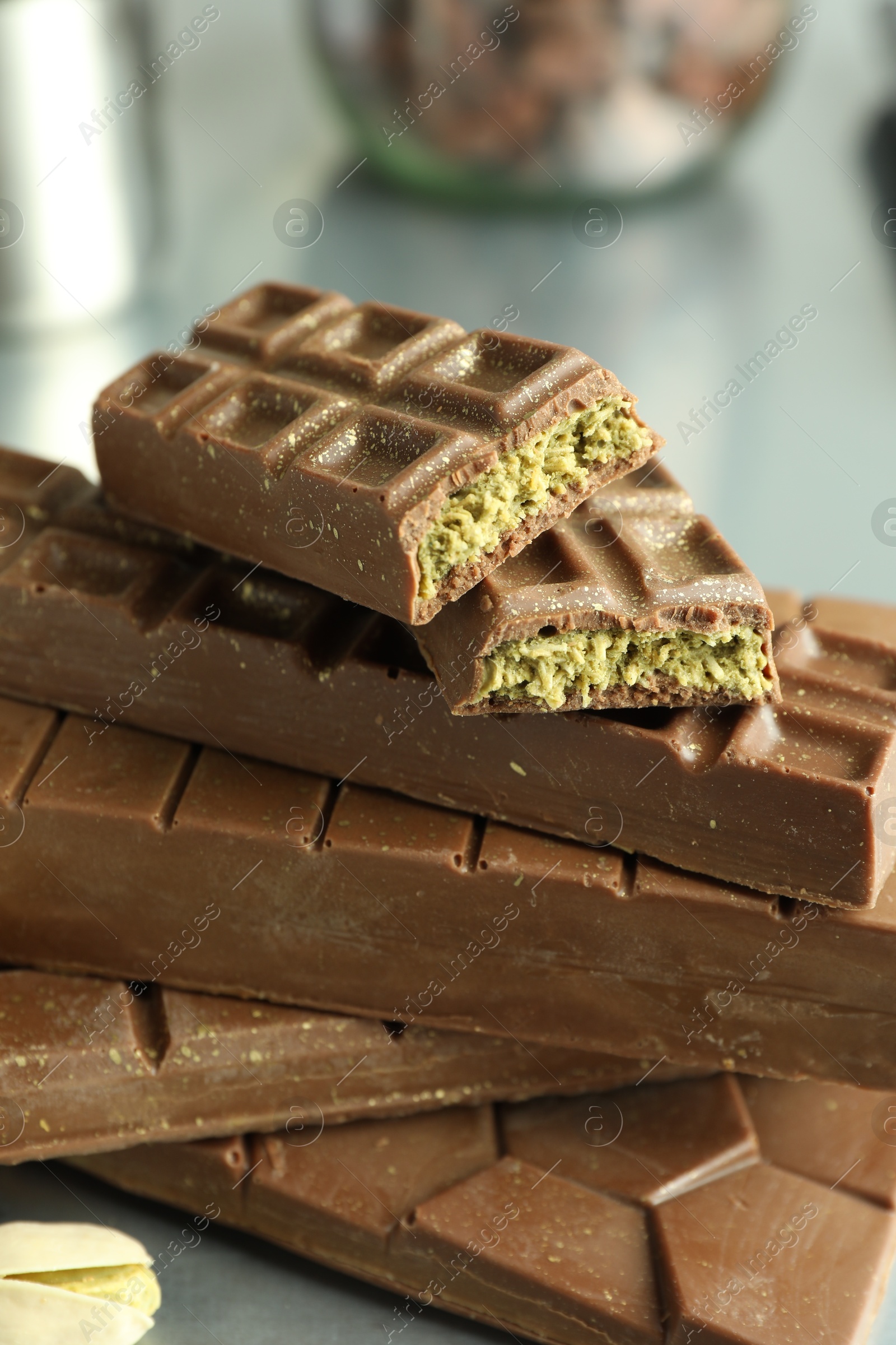 Photo of Stack of tasty Dubai chocolate bars with pistachios and knafeh on grey table, closeup