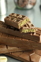 Photo of Stack of tasty Dubai chocolate bars with pistachios and knafeh on grey table, closeup