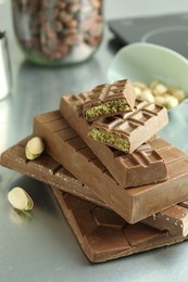 Photo of Stack of tasty Dubai chocolate bars with pistachios and knafeh on grey table, closeup