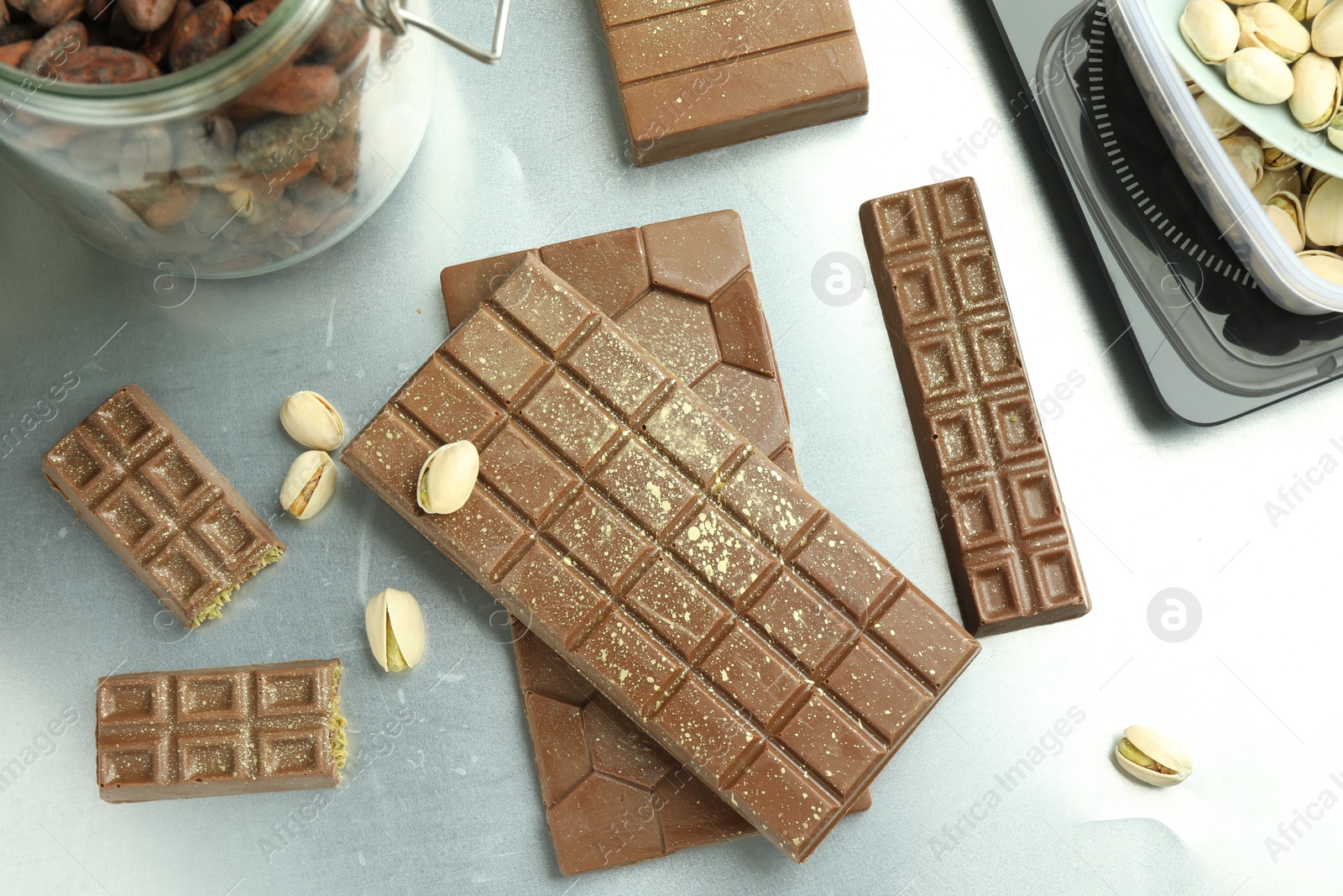 Photo of Different tasty Dubai chocolate bars with pistachios and knafeh on grey table, flat lay