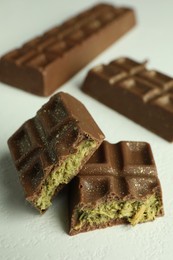 Photo of Pieces of tasty Dubai chocolate with pistachios and knafeh on white textured table, closeup