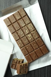 Photo of Tasty Dubai chocolate with pistachios and knafeh on black wooden table, top view