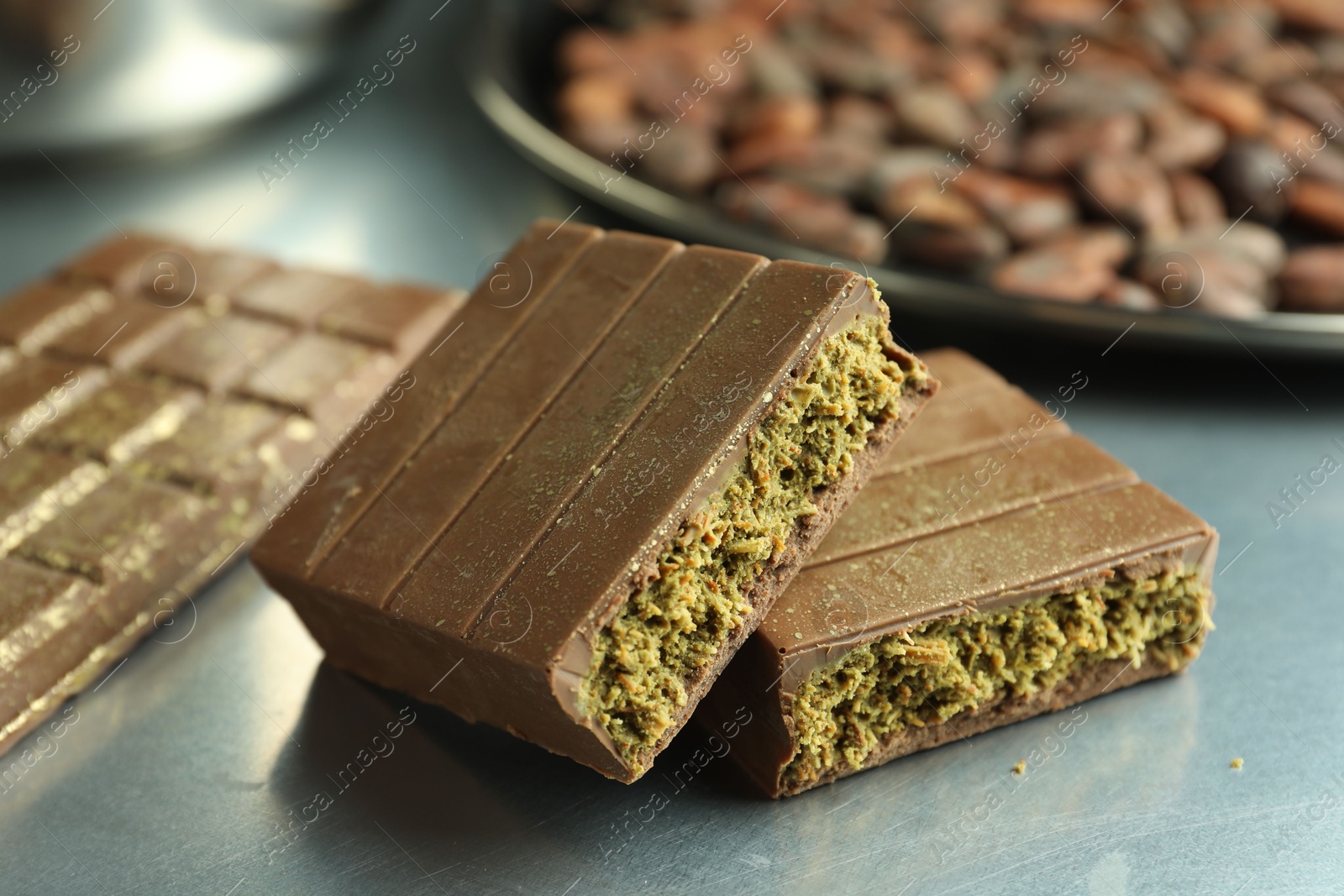 Photo of Pieces of tasty Dubai chocolate with pistachios and knafeh on grey table, closeup