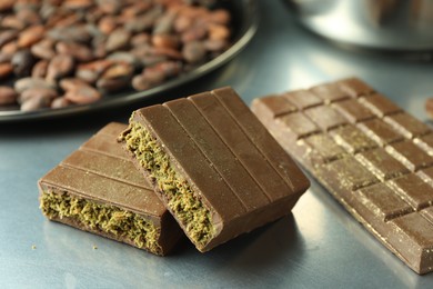 Photo of Pieces of tasty Dubai chocolate with pistachios and knafeh on grey table, closeup