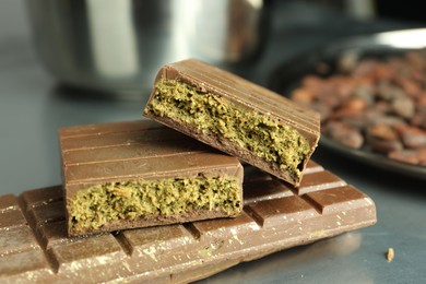 Photo of Tasty Dubai chocolate with pistachios and knafeh on grey table, closeup