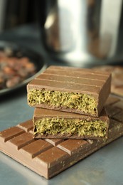 Photo of Tasty Dubai chocolate with pistachios and knafeh on grey table, closeup