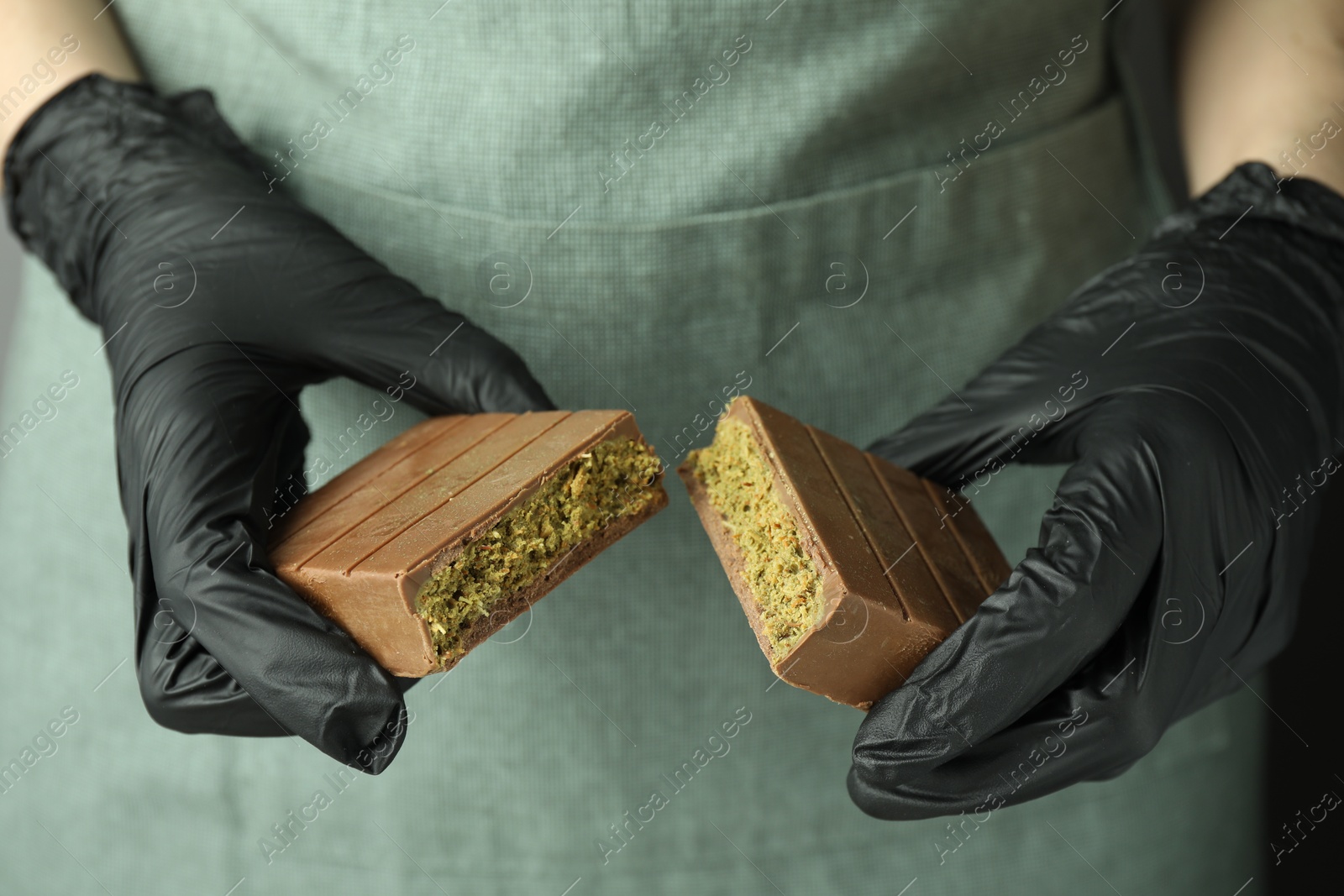 Photo of Woman holding pieces of tasty Dubai chocolate with pistachios and knafeh, closeup