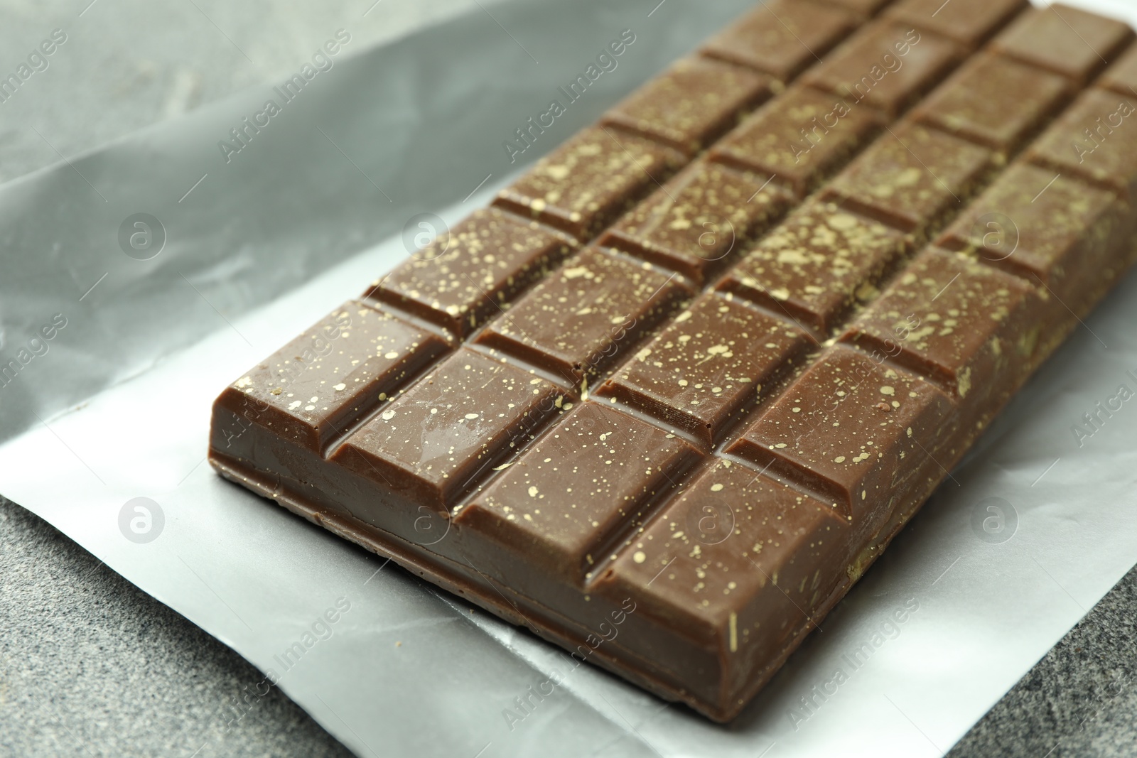 Photo of One tasty Dubai chocolate bar with pistachios and knafeh on grey textured table, closeup