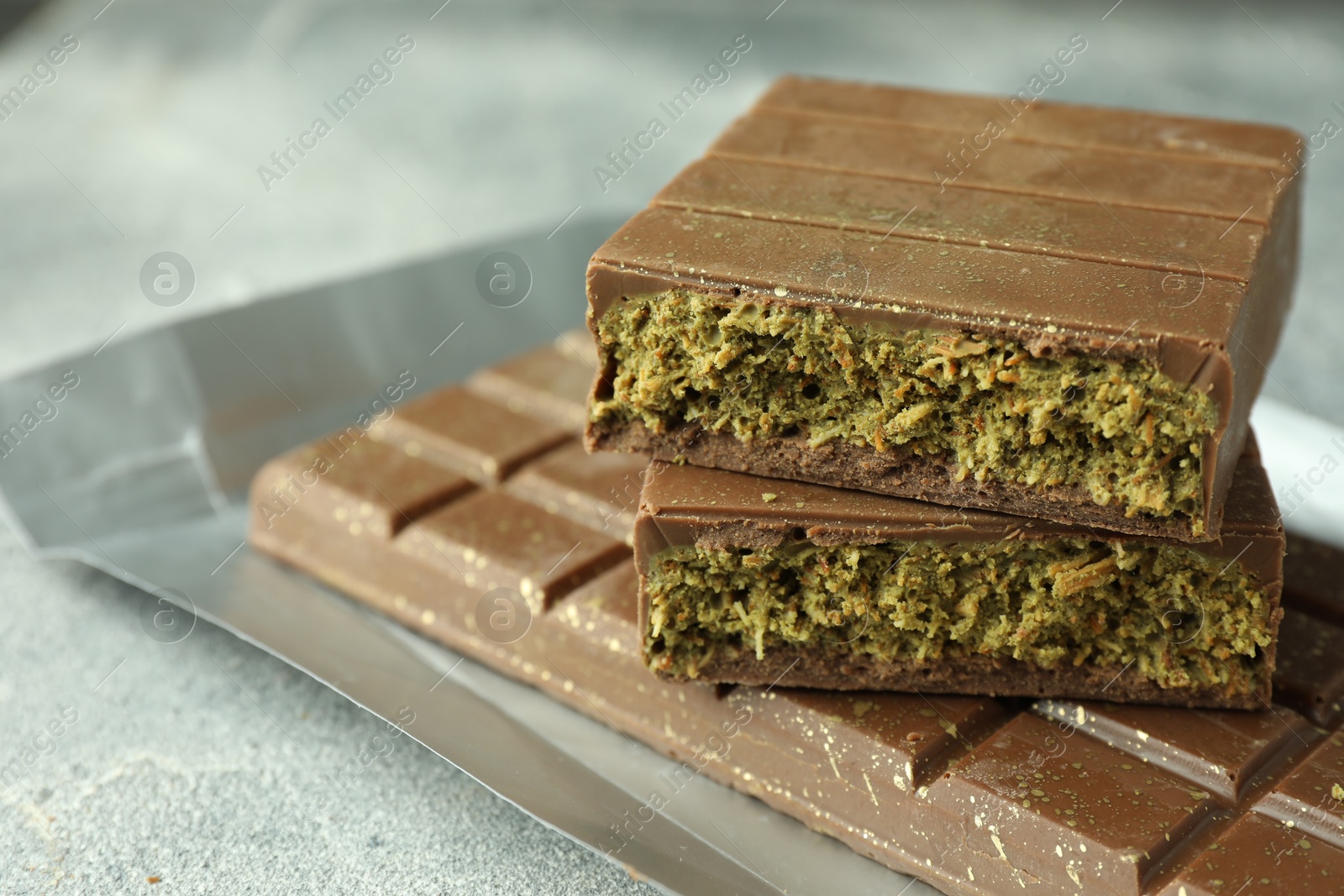 Photo of Tasty Dubai chocolate with pistachios and knafeh on grey textured table, closeup