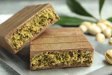 Photo of Pieces of tasty Dubai chocolate with pistachios and knafeh on grey textured table, closeup