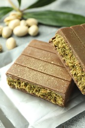 Photo of Pieces of tasty Dubai chocolate with pistachios and knafeh on grey textured table, closeup