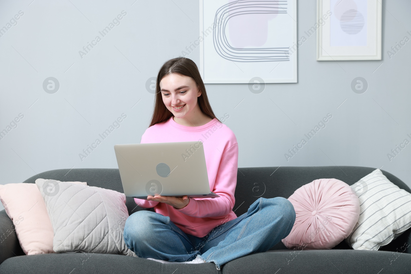 Photo of Smiling young woman working on laptop at home