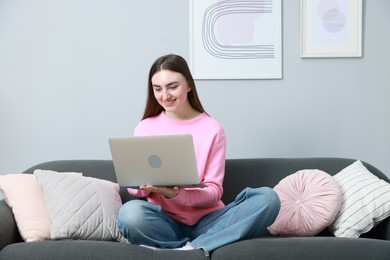 Photo of Smiling young woman working on laptop at home