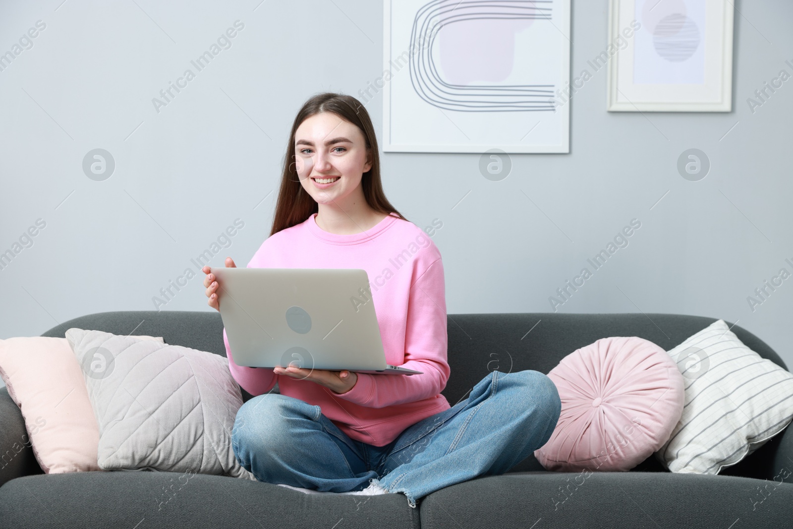 Photo of Smiling young woman working on laptop at home