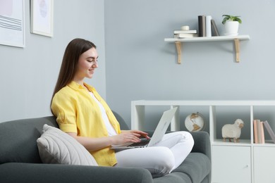 Photo of Young woman using laptop on sofa at home