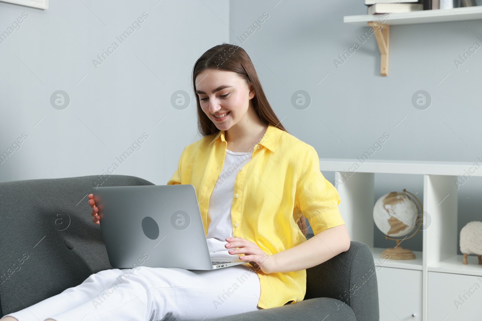 Photo of Young woman using laptop on sofa at home