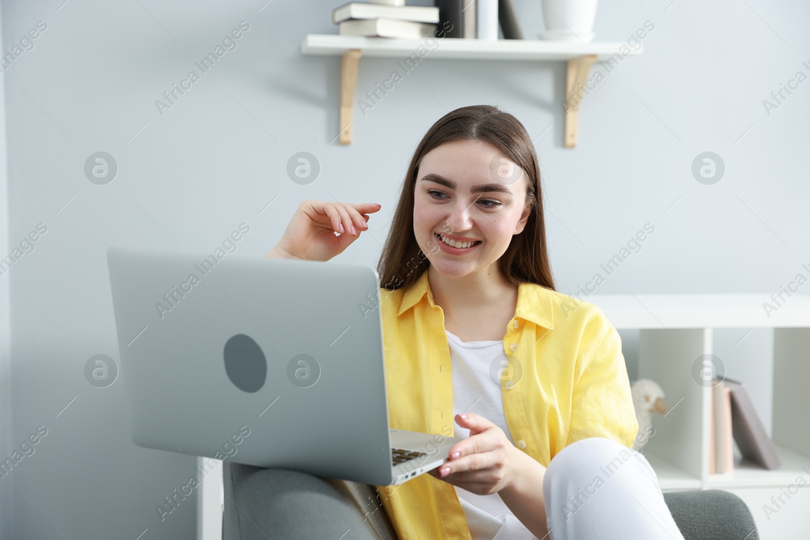 Photo of Young woman using laptop on sofa at home