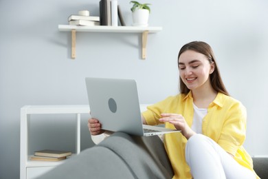 Photo of Young woman using laptop on sofa at home