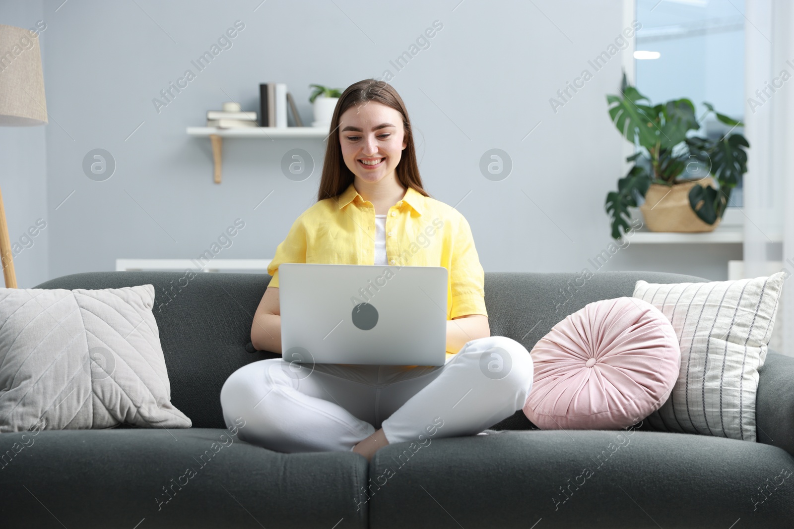 Photo of Young woman using laptop on sofa at home