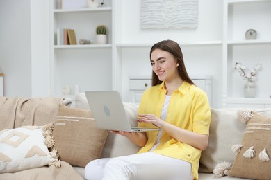 Photo of Smiling young woman working on laptop at home