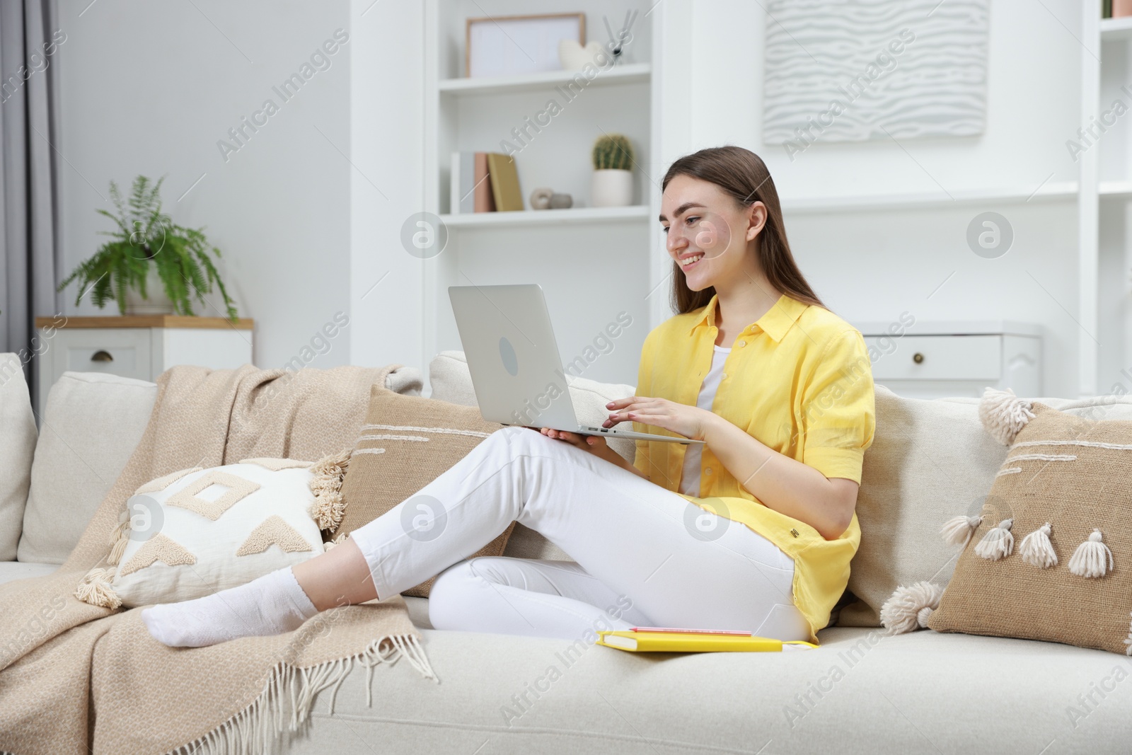 Photo of Smiling young woman working on laptop at home