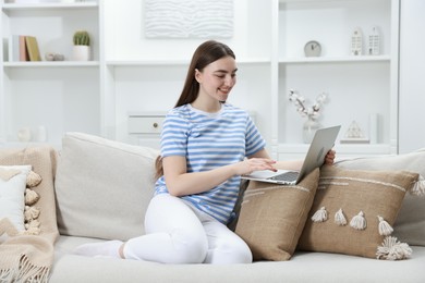 Photo of Young woman using laptop on sofa at home