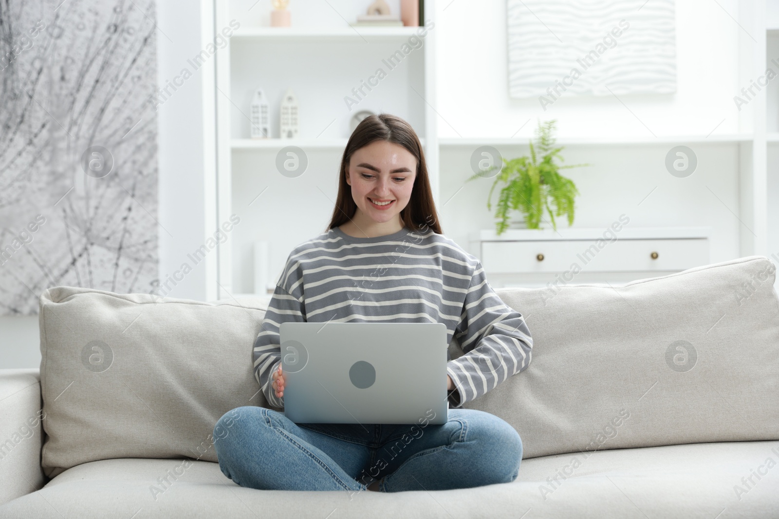 Photo of Young woman using laptop on sofa at home