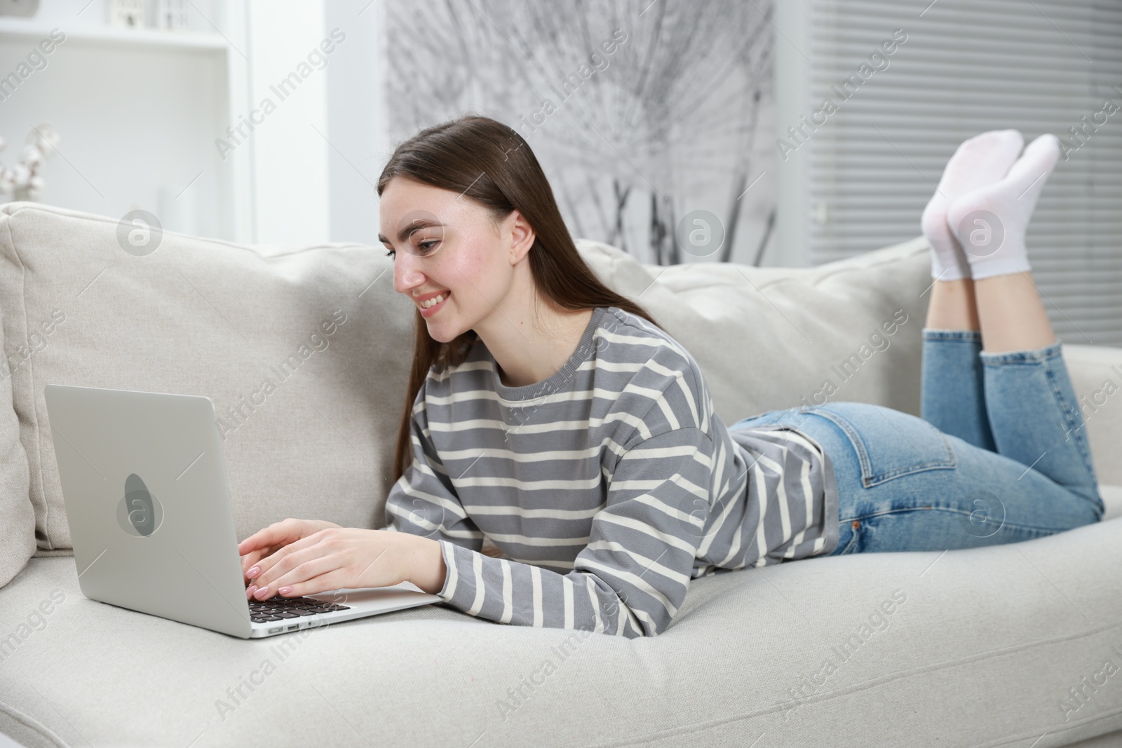 Photo of Young woman using laptop on sofa at home