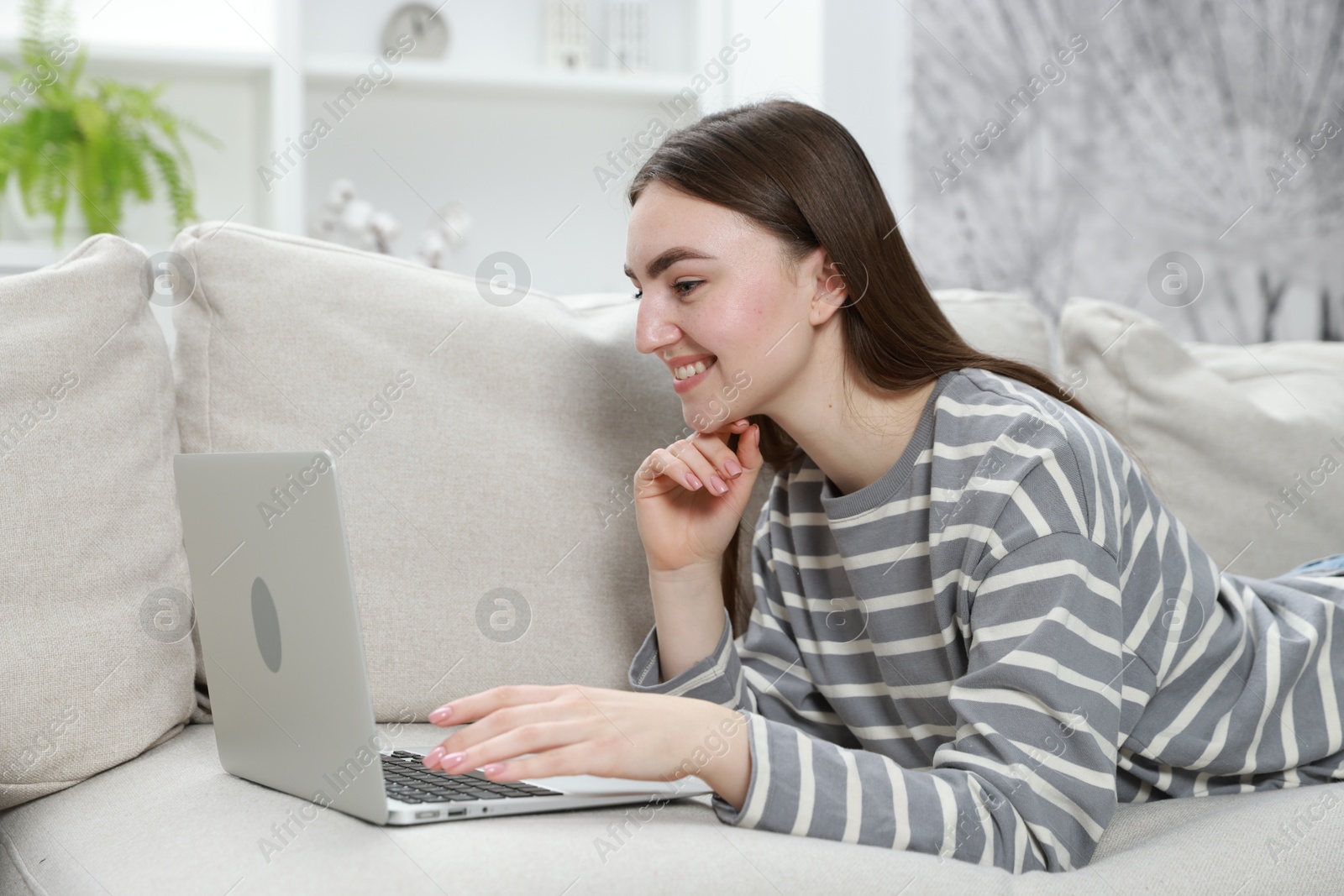 Photo of Young woman using laptop on sofa at home