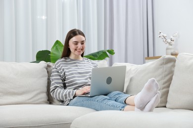 Photo of Young woman using laptop on sofa at home