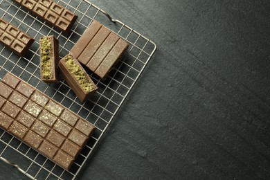 Delicious Dubai chocolate bars with pistachios and knafeh on black table, top view. Space for text