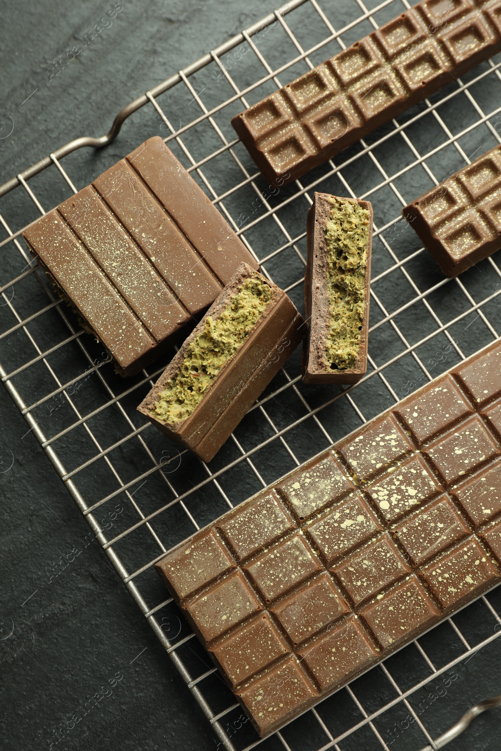 Photo of Delicious Dubai chocolate bars with pistachios and knafeh on black table, top view