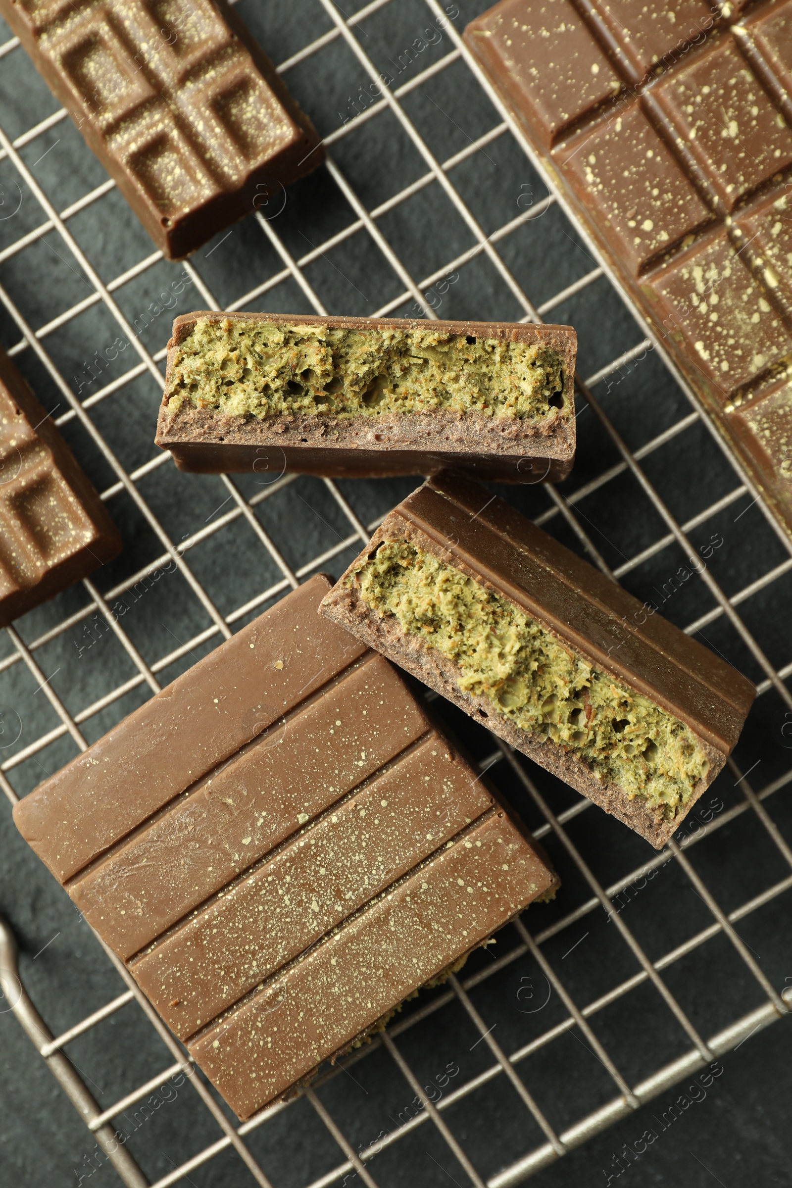 Photo of Delicious Dubai chocolate bars with pistachios and knafeh on black table, top view