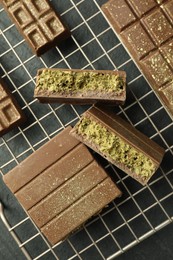 Photo of Delicious Dubai chocolate bars with pistachios and knafeh on black table, top view