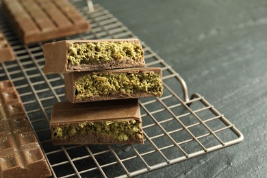 Photo of Pieces of delicious Dubai chocolate with pistachios and knafeh on black table, closeup