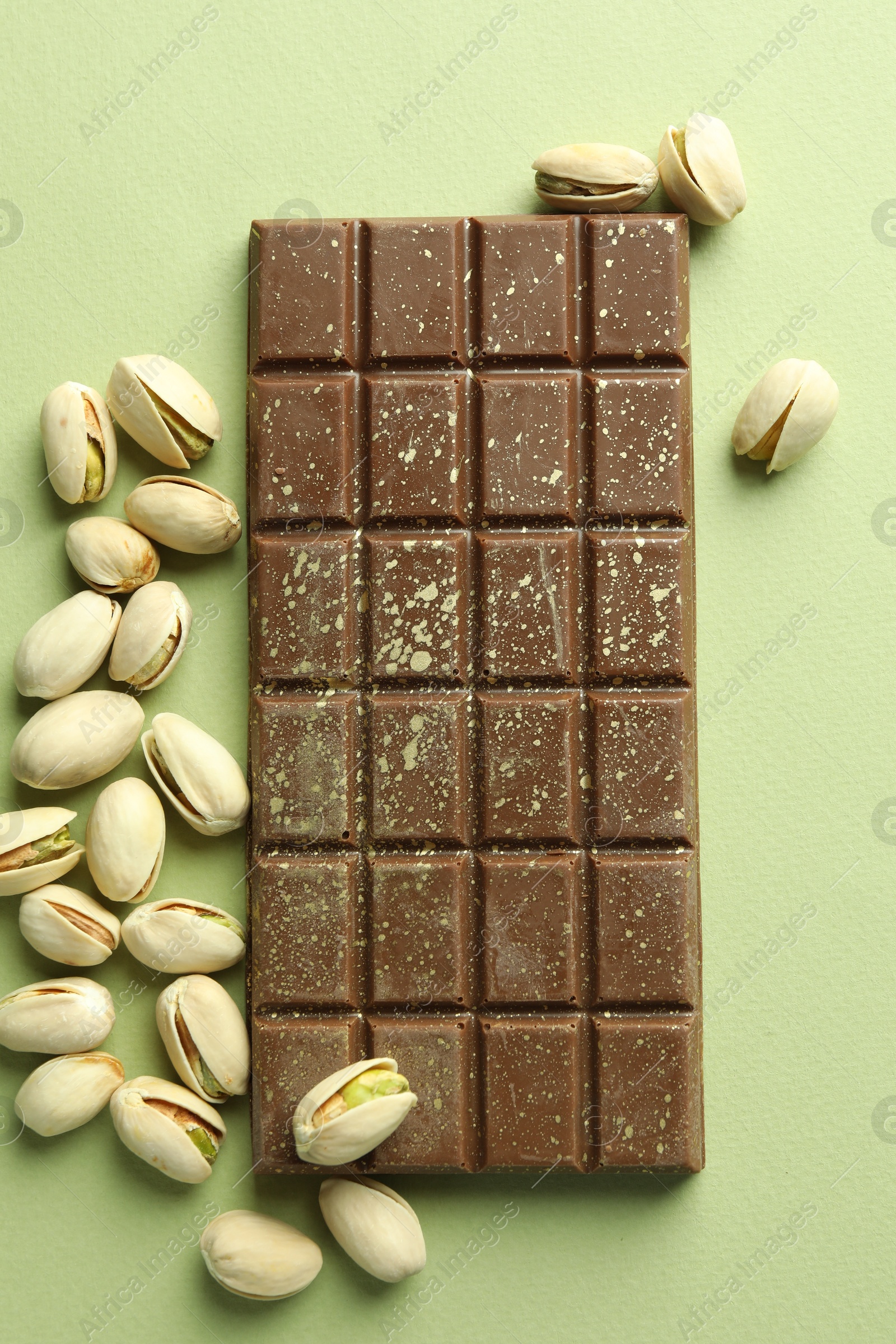 Delicious Dubai chocolate with pistachios and knafeh on green background, flat lay Photo of Delicious Dubai chocolate with pistachios and knafeh on green background, flat lay