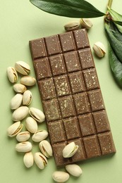 Delicious Dubai chocolate with pistachios and knafeh on green background, flat lay