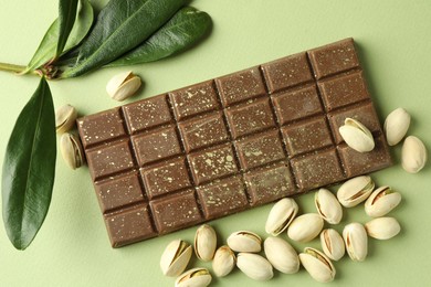 Delicious Dubai chocolate with pistachios and knafeh on green background, flat lay