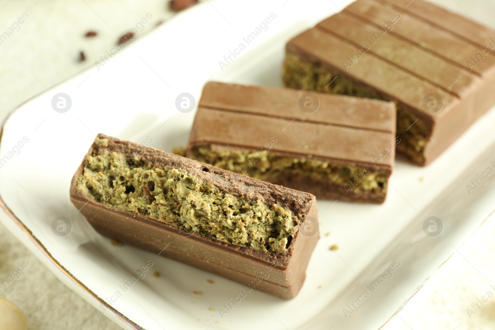 Photo of Pieces of delicious Dubai chocolate with pistachios and knafeh on table, closeup