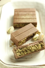 Photo of Pieces of delicious Dubai chocolate with pistachios and knafeh on table, closeup