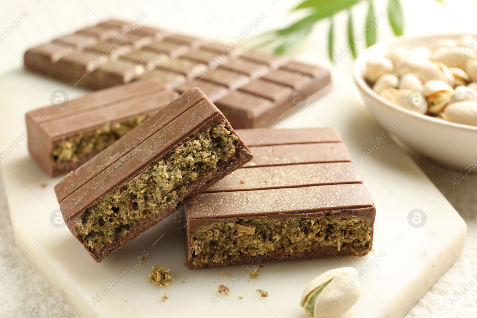 Photo of Pieces of delicious Dubai chocolate with pistachios and knafeh on table, closeup