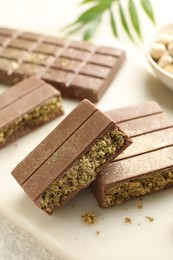 Photo of Pieces of delicious Dubai chocolate with pistachios and knafeh on table, closeup