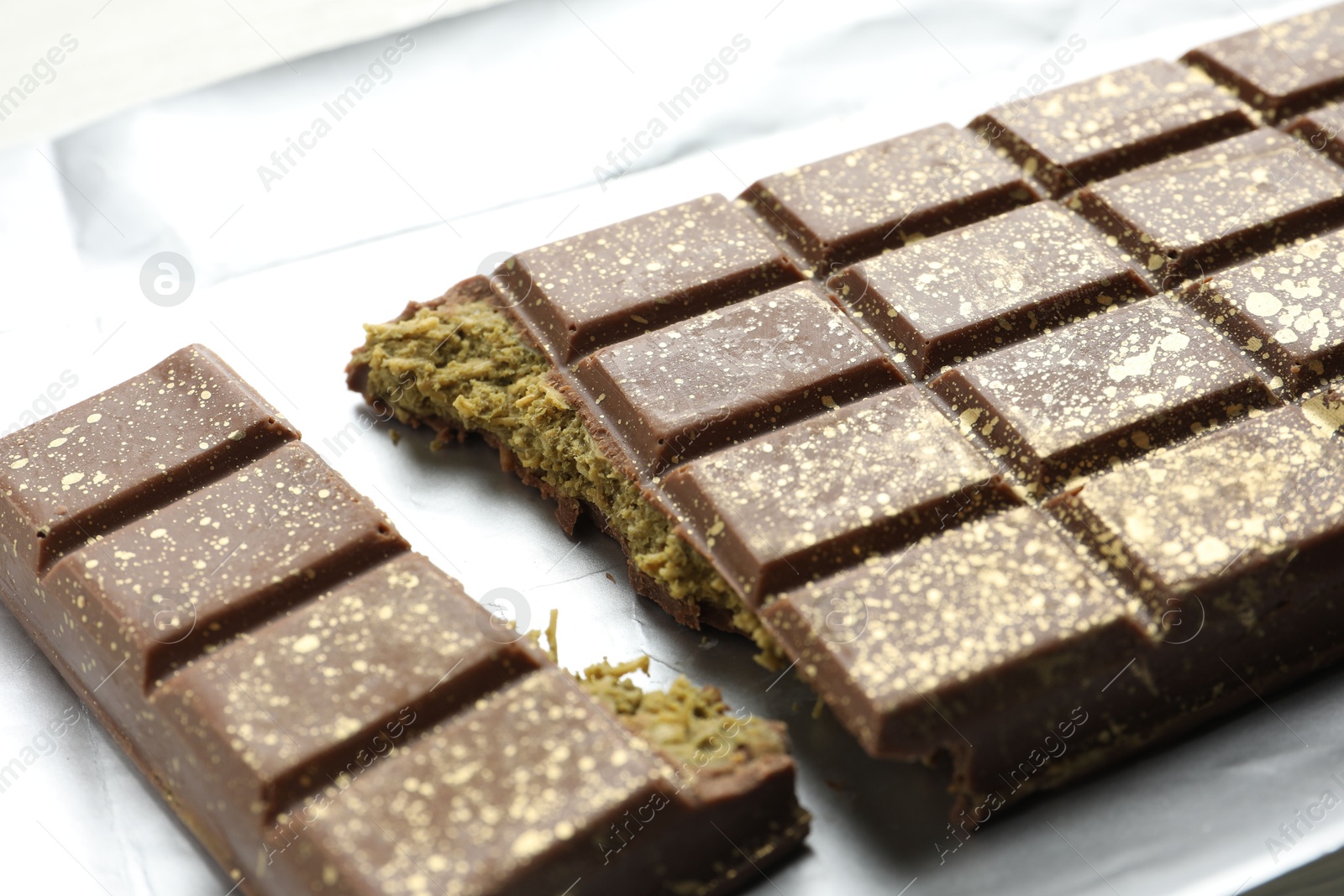 Photo of Delicious Dubai chocolate with pistachios and knafeh on table, closeup