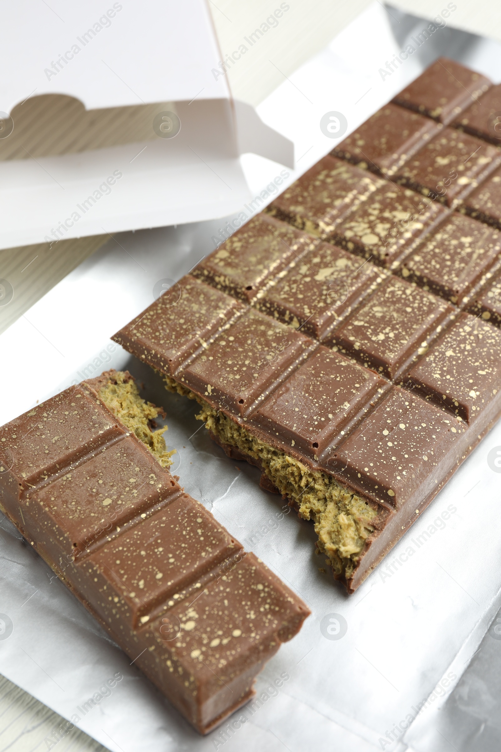 Photo of Delicious Dubai chocolate with pistachios and knafeh on table, closeup